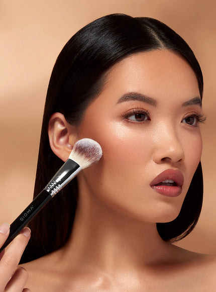 A model using a makeup brush on her face