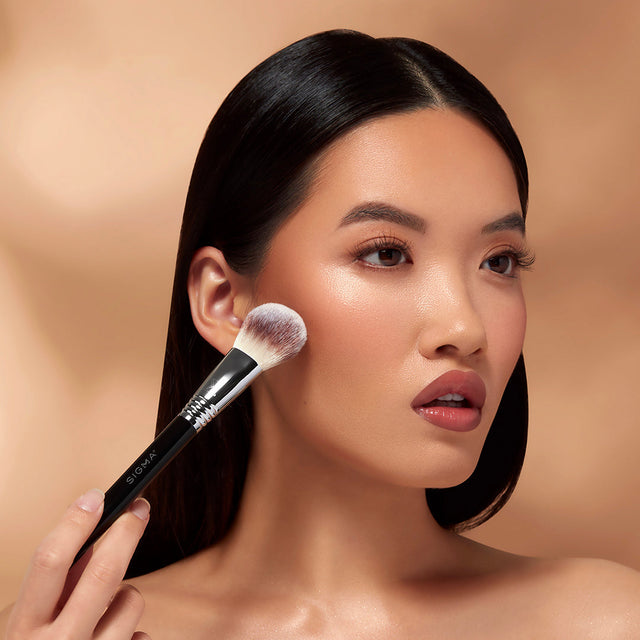 A model using a makeup brush on her face