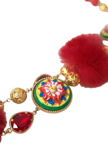 a close up of a necklace with a red pom pom