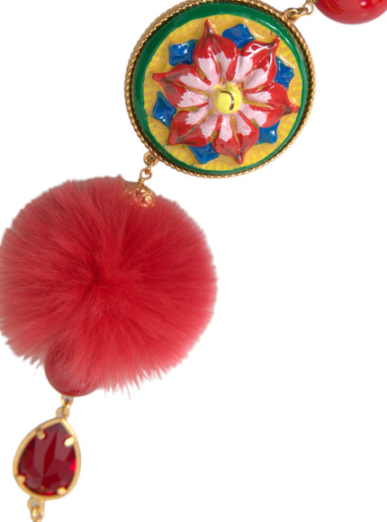 a red pom pom hanging from a gold chain