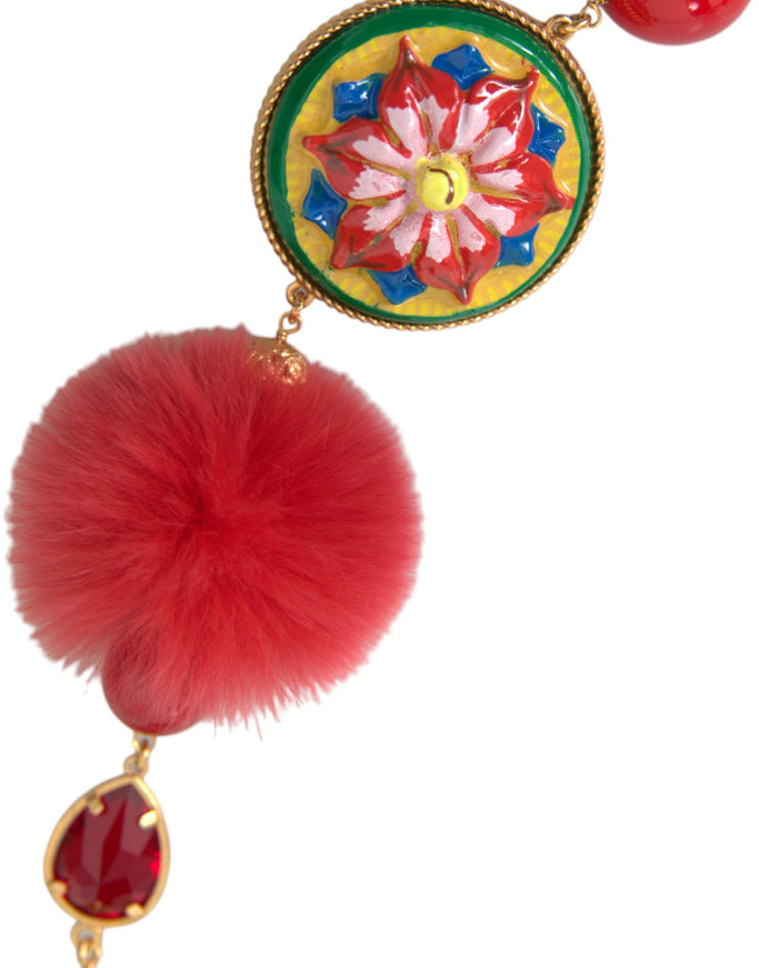 a red pom pom hanging from a gold chain