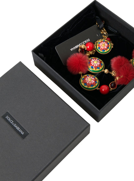 a pair of red and green earrings in a black box