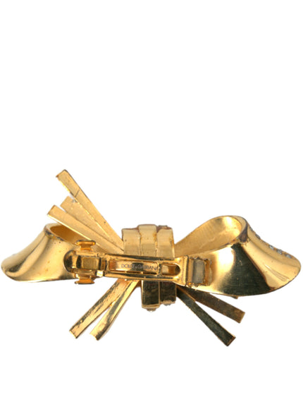 a close up of a gold bow brooch on a white background