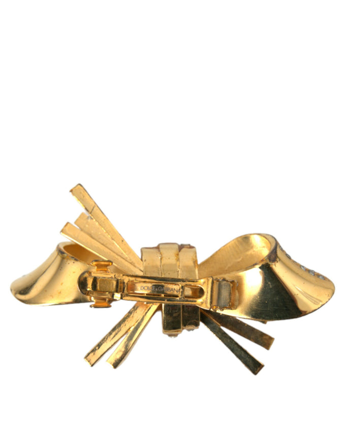 a close up of a gold bow brooch on a white background