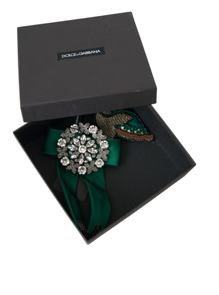 a black box with a green ribbon and a brooch