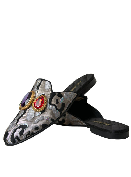 a pair of black and silver slippers with a red jewel