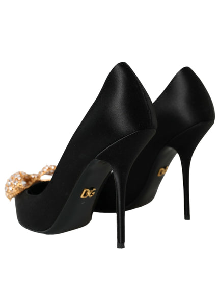 a pair of black high heels with a gold bow