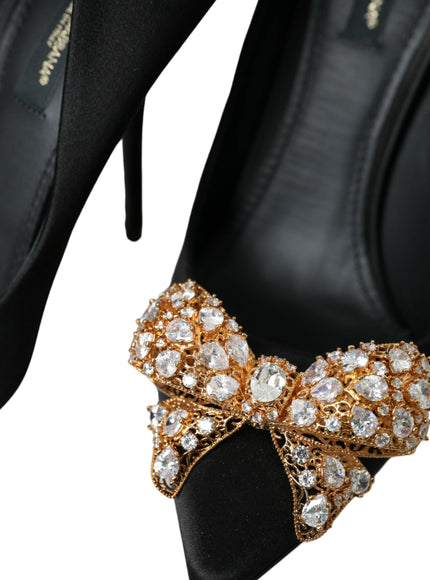 a pair of black high heels with a gold bow