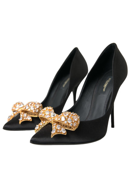 a pair of black high heels with a gold bow