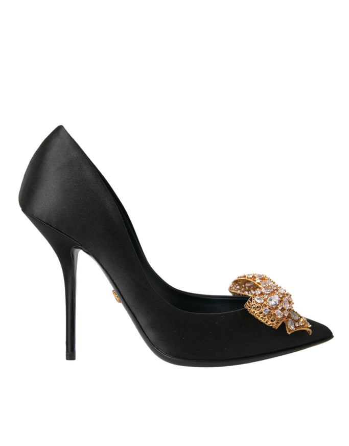 a black high heel shoe with a gold bow