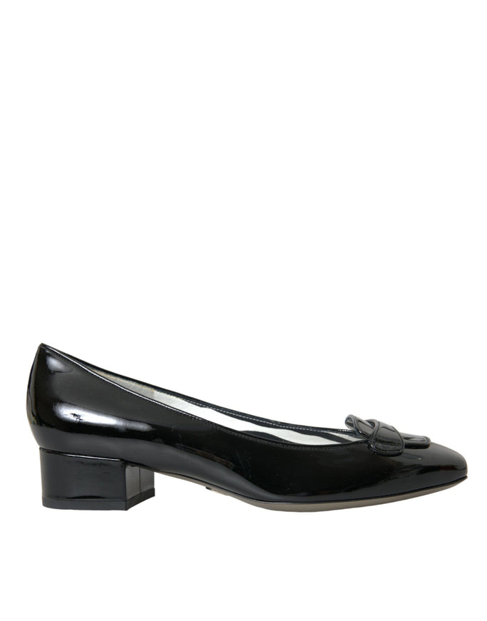 a pair of black shoes with a bow on the heel