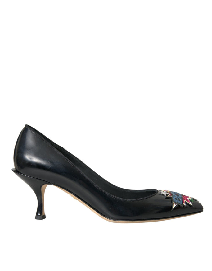 a woman's black high heeled shoe with a flower decoration