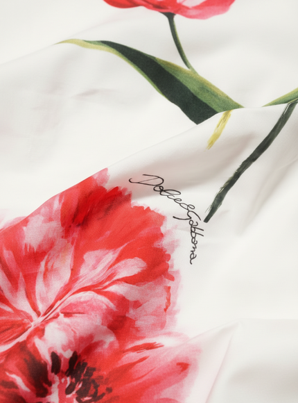 Close-up of a floral design with red flowers and green leaves on a white background.