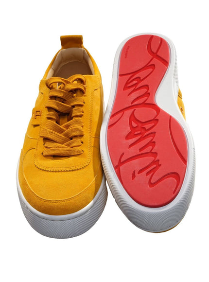 a pair of yellow sneakers with red soles