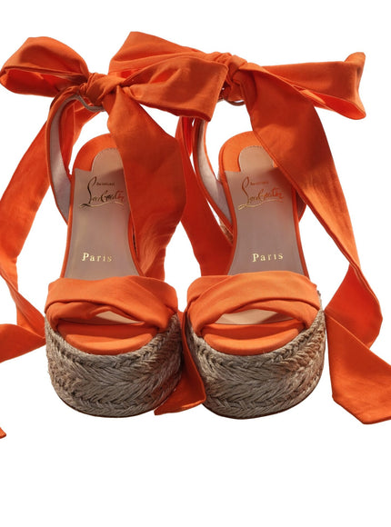 a pair of orange high heeled shoes with a bow