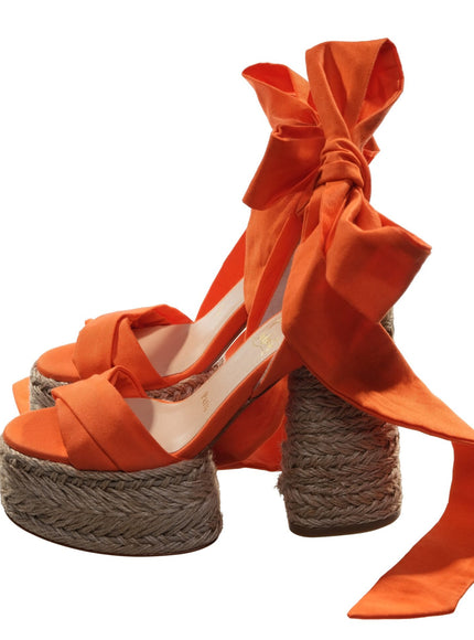 a pair of orange shoes with a bow tied to them