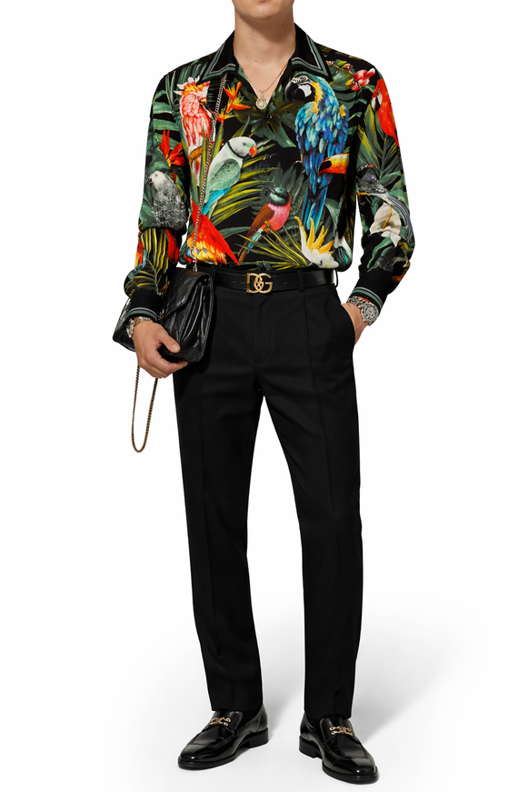 Person wearing a colorful parrot-themed shirt with black pants and shoes on a white background