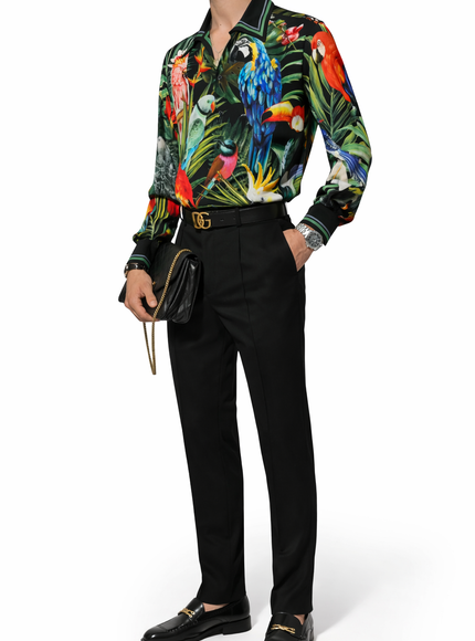 Person wearing a colorful parrot print shirt with black pants on a white background