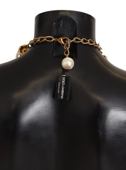 a black mannequin with a gold chain and a pearl