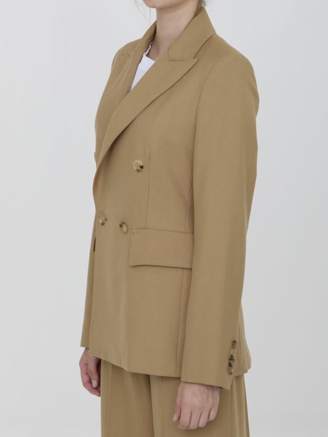 a woman wearing a tan suit and hat