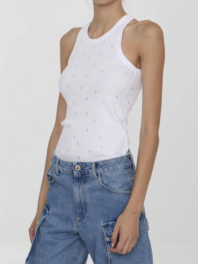 a woman wearing a white tank top and jeans