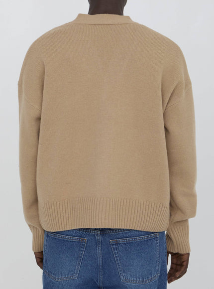 a man wearing a tan sweater and jeans