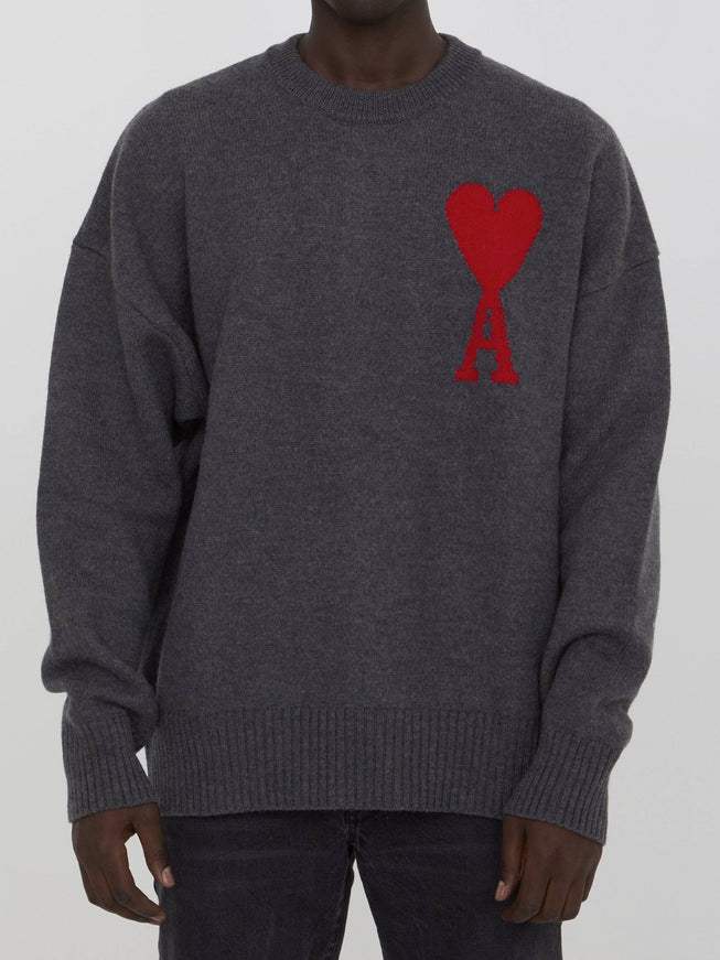 a man wearing a grey sweater with a red heart on it