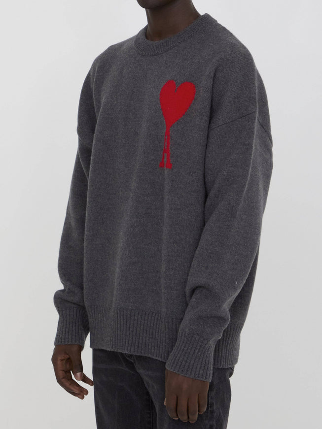 a man wearing a grey sweater with a red heart on it