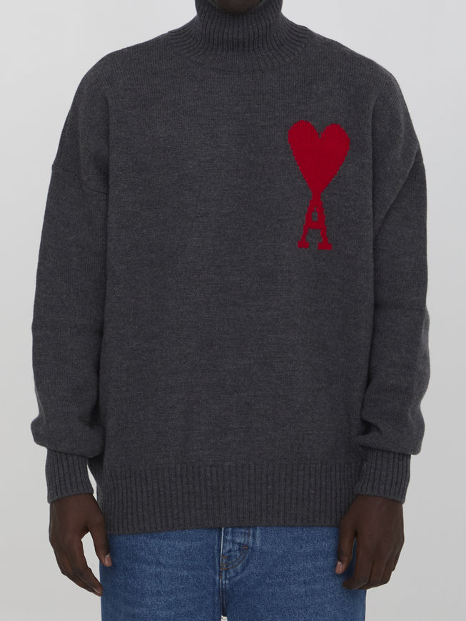 a man wearing a grey sweater with a red heart on it