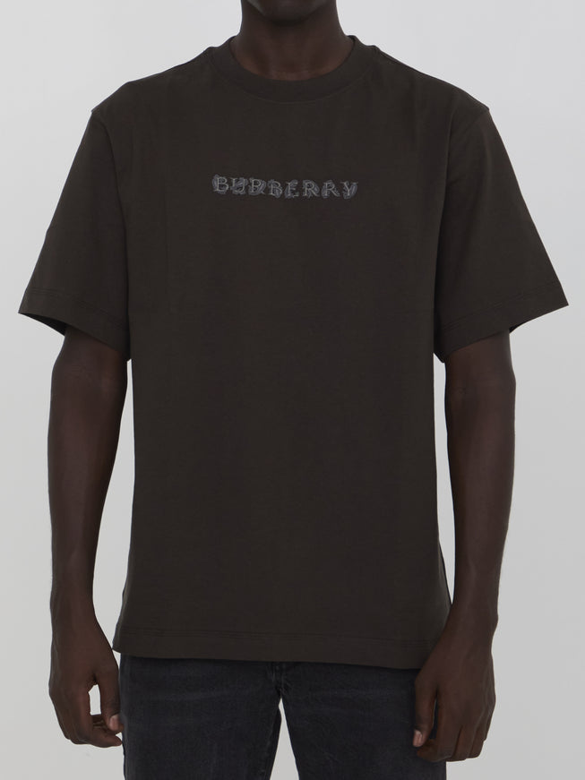 a man wearing a brown shirt with the word ordinary printed on it