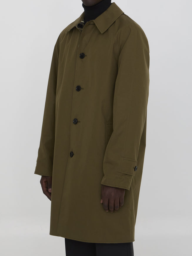 a man in a trench coat standing in front of a white background