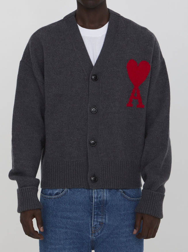 a man wearing a grey cardigan with a red heart on it