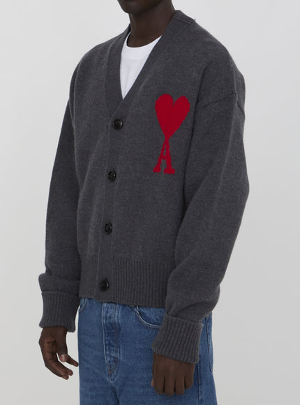 a man wearing a grey cardigan with a red heart on it