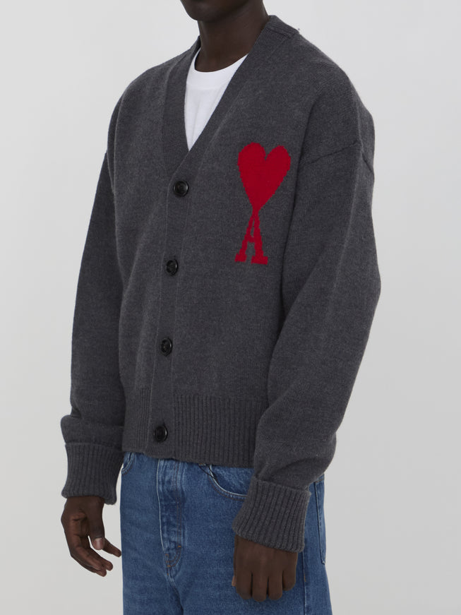 a man wearing a grey cardigan with a red heart on it