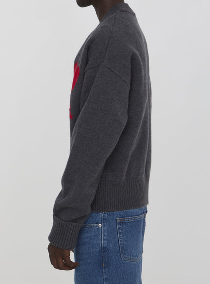 a man wearing a grey sweater with a red heart on it