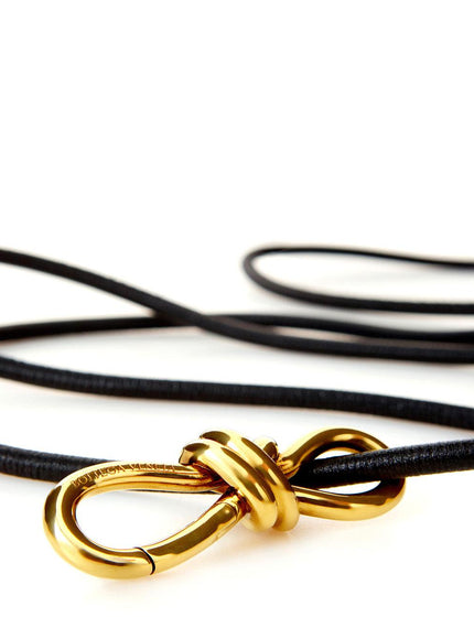 Close-up of gold knot buckle on black leather belt