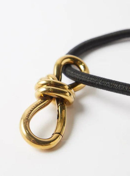 Detailed view of gold knot buckle on black leather belt