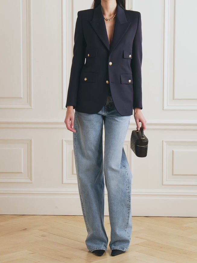 a woman standing in a room wearing a jacket and jeans