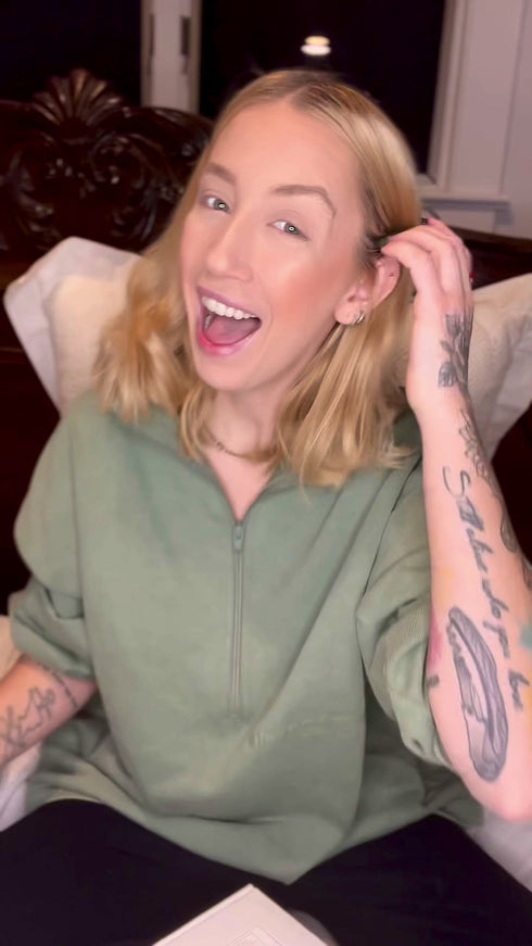 Person smiling with tattoos and wearing a green shirt