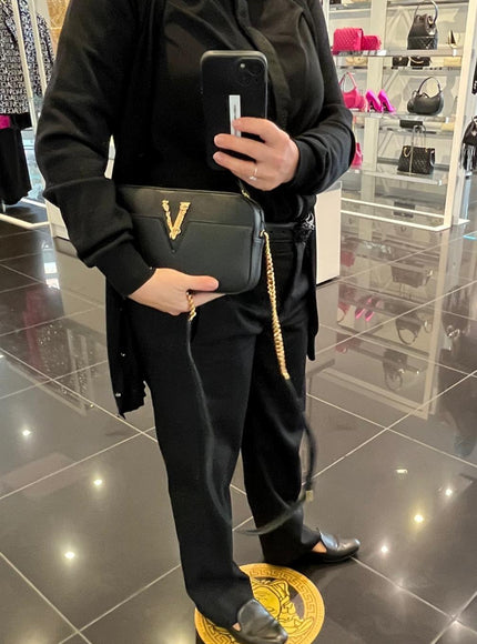 Model showcasing Versace black Virtus bag with gold chain